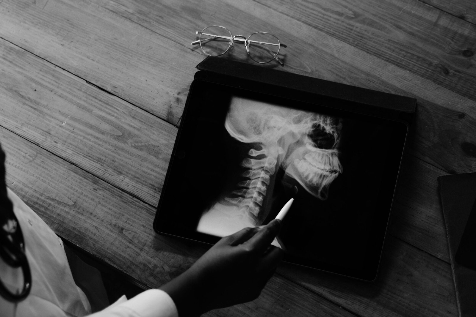 A doctor examining an X-ray image on a tablet in a medical setting, focusing on a patient's neck.